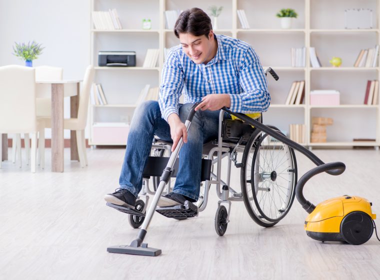 Disabled man cleaning home with vacuum cleaner