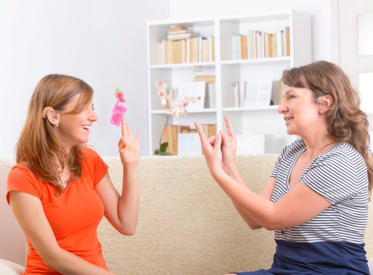 Smiling deaf woman learning sign language and talking with her teacher